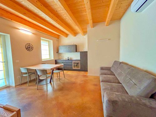 Ampio soggiorno con cucina a vista e soffitto con travi in legno