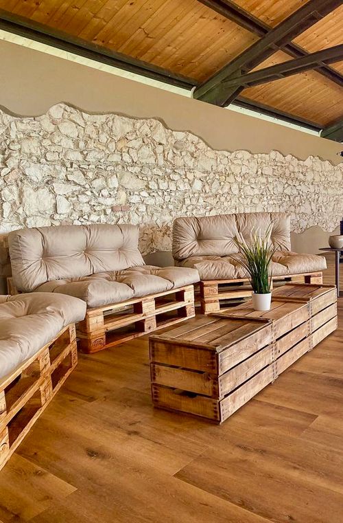 Lounge esterna con divani in pallet e muro in pietra